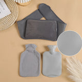 Bouillotte Tour de Taille grise en flanelle avec housse amovible, posee sur fond beige avec accessoires decoratifs