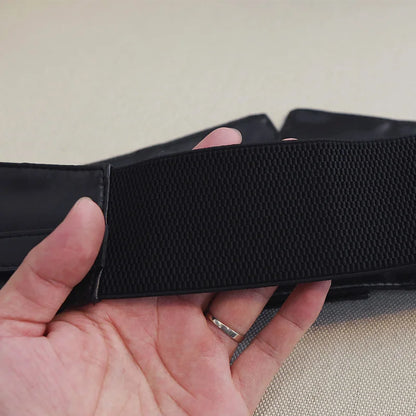 Ceinture Simili Cuir Corset noire tenue à la main, détail du matériau élastique et simili cuir PU pour un maintien élégant.