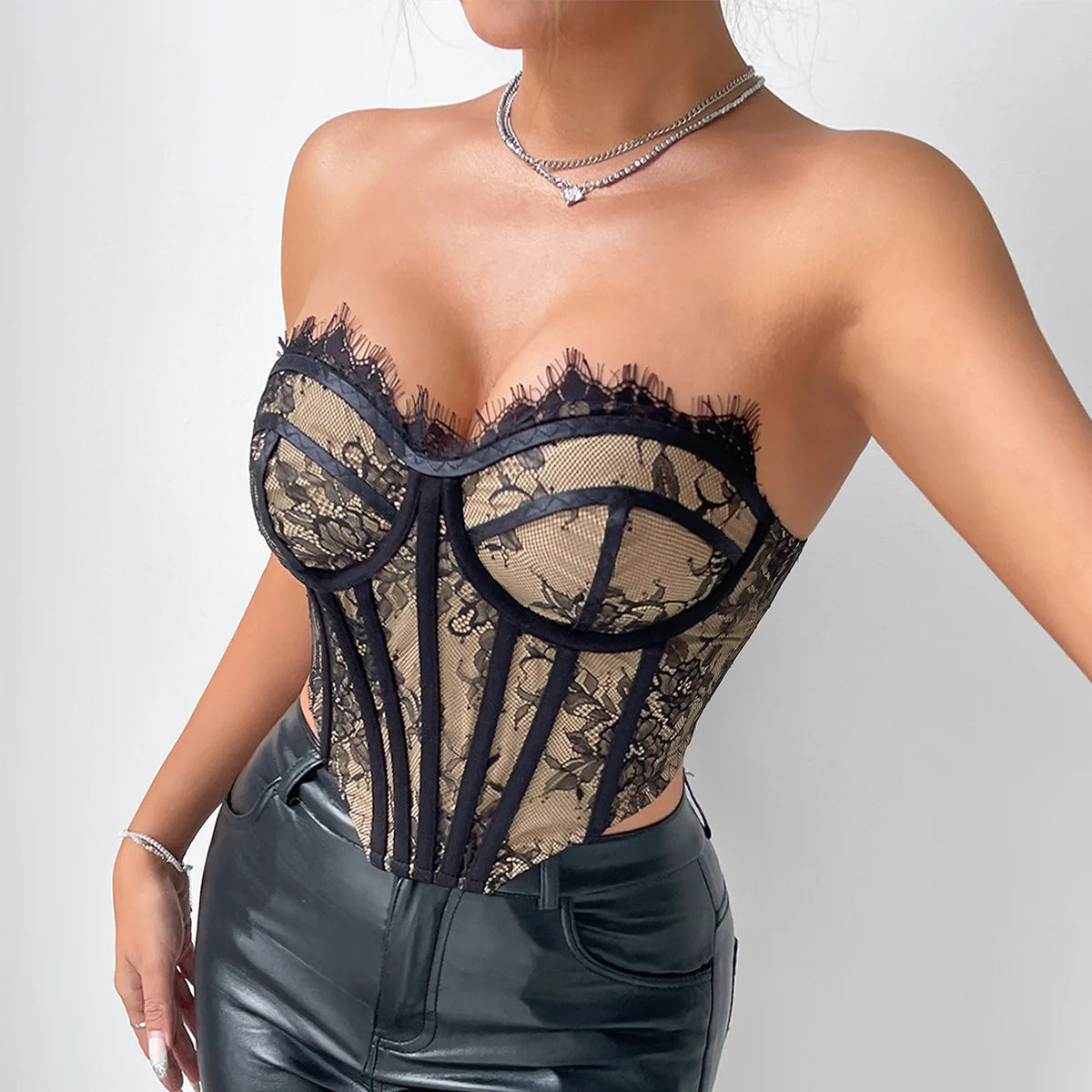 Bustier Dos Nu en dentelle noire et beige avec details corset elegant, porte avec un collier argente et un pantalon en cuir noir