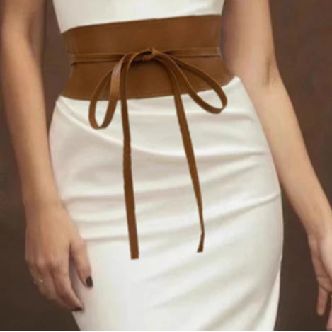 Ceinture corset cuir marron portee avec une robe blanche moulante, nouee elegamment a la taille