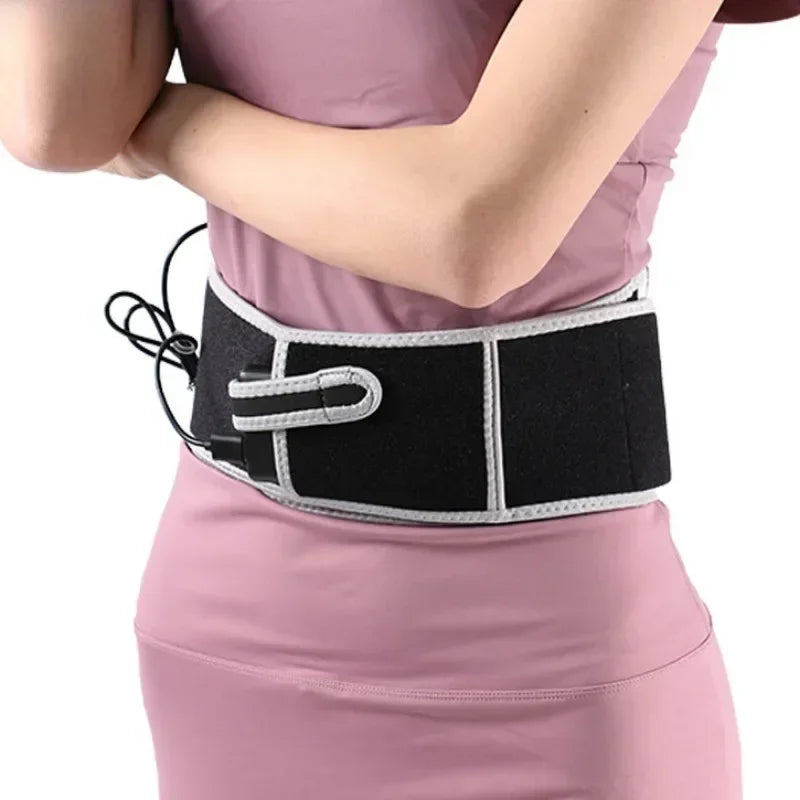 Ceinture lombaire chauffante noire avec bordure grise portee sur une tenue rose, vue laterale du produit en utilisation